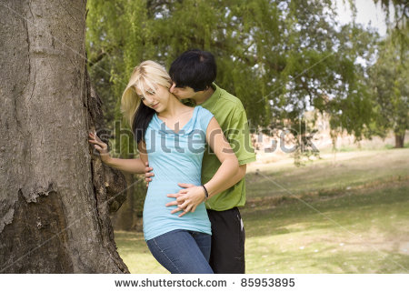 Stock-photo-boyfriend-kissing-girlfriend-neck-next-to-garden-tree-85953895